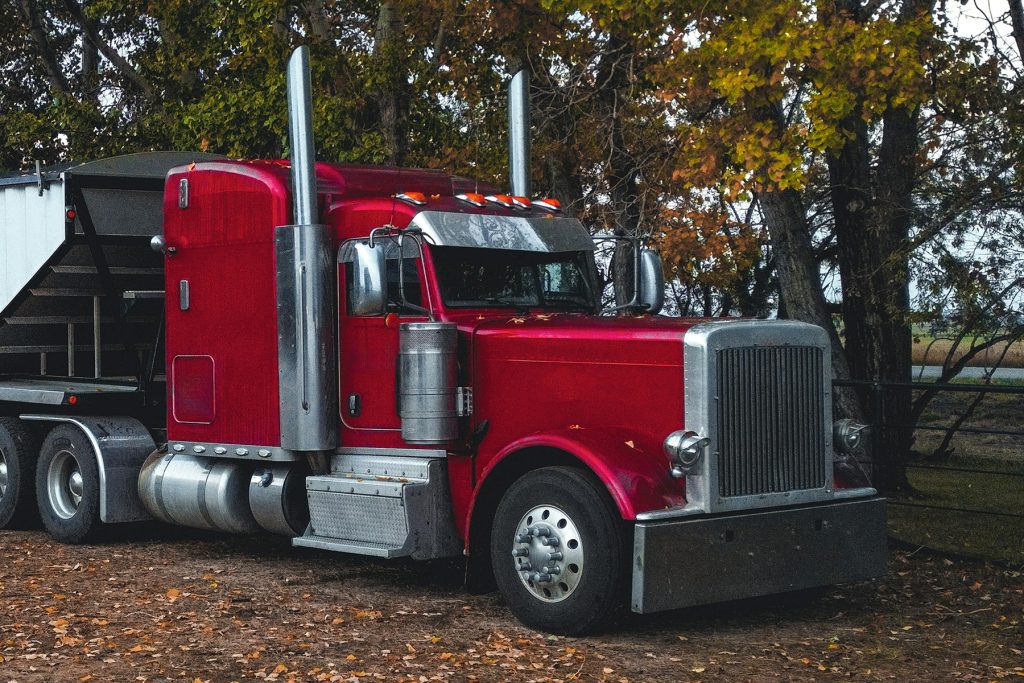 Red transport truck parked on a rural property.