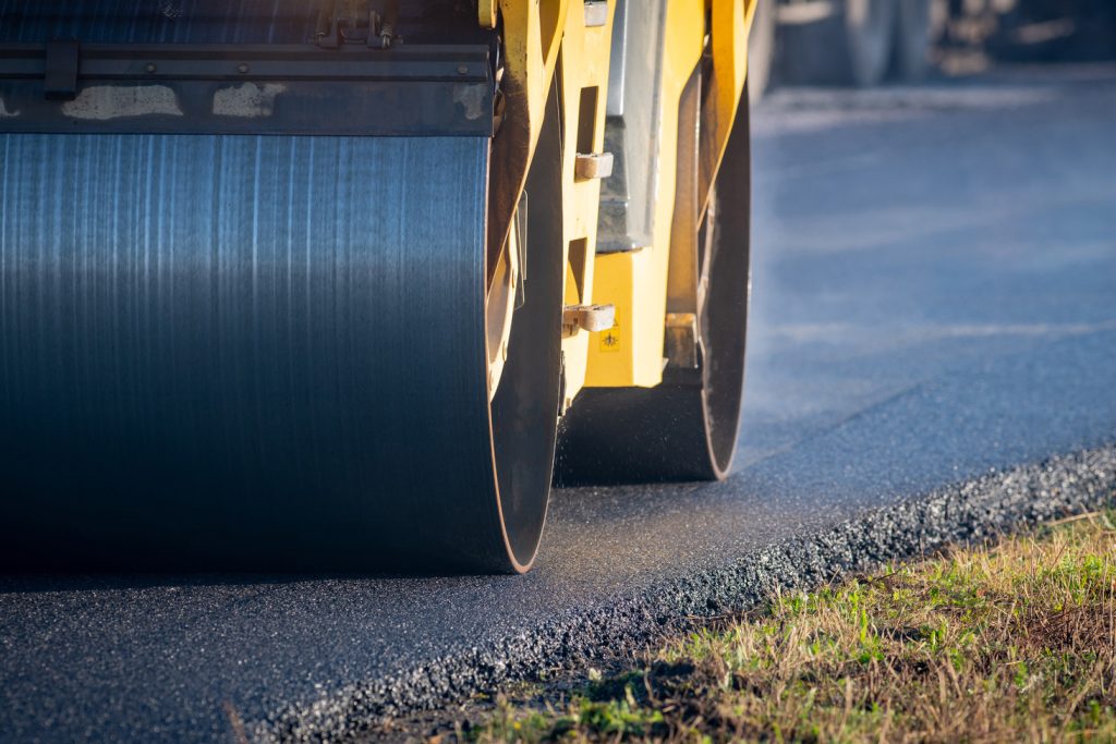 Road roller compacting fresh asphalt during road resurfacing.